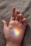 A hand is laid open on a soft, textured surface. A small rainbow is projected onto the palm, displaying a spectrum of colors vividly against the skin.