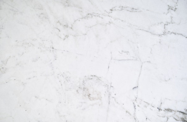 Close-up of a sleek white quartz kitchen countertop with subtle gray veining under soft natural light.