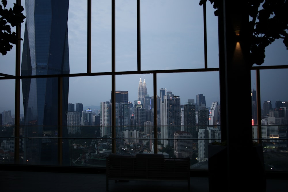 Un banco sentado frente a una ventana con vistas a una ciudad