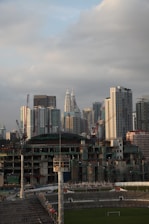 Construction workers laying out a new urban sports field with city buildings in the background.