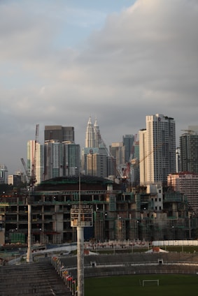 Construction workers laying out a new urban sports field with city buildings in the background.