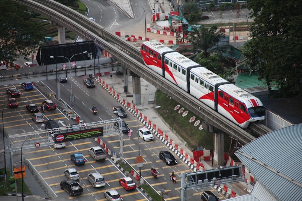 um trem vermelho e branco viajando sobre uma rua da cidade