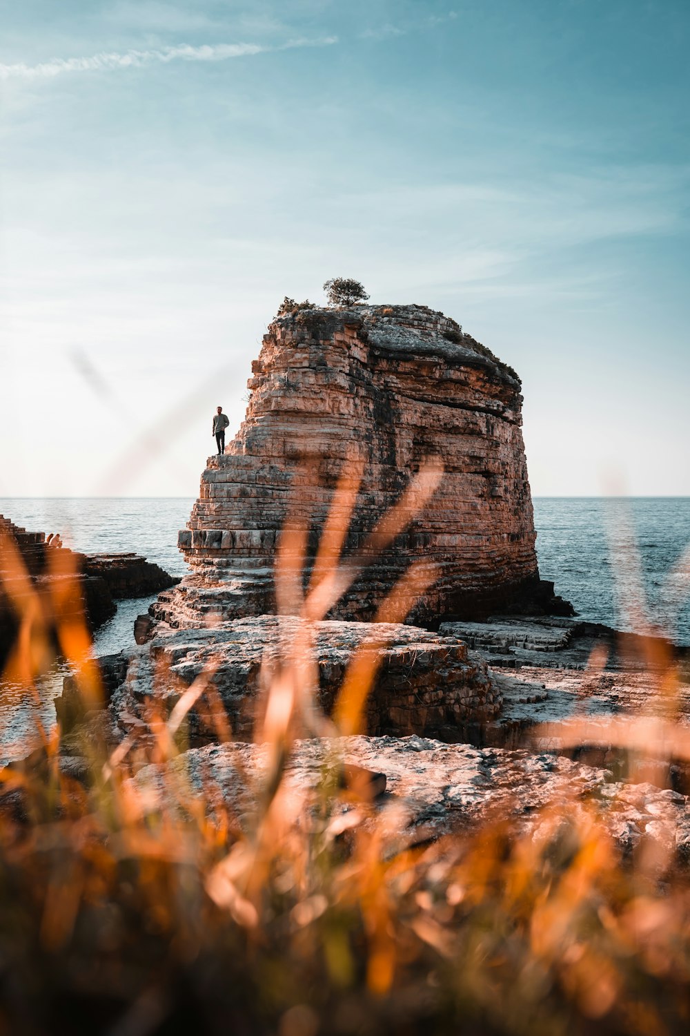 a man standing on top of a large rock near the ocean