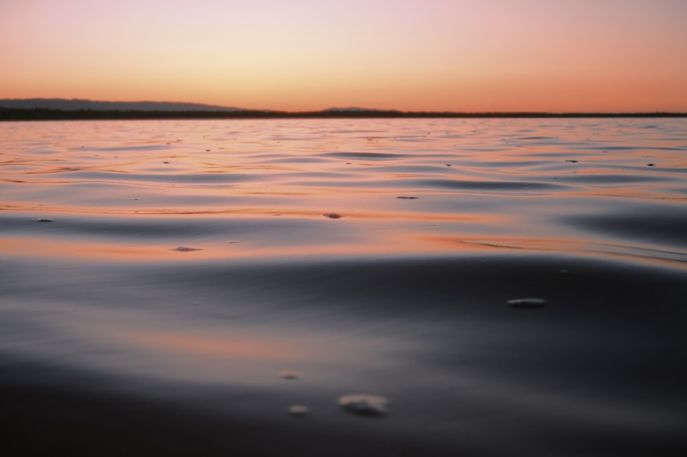 a body of water with a sunset in the background