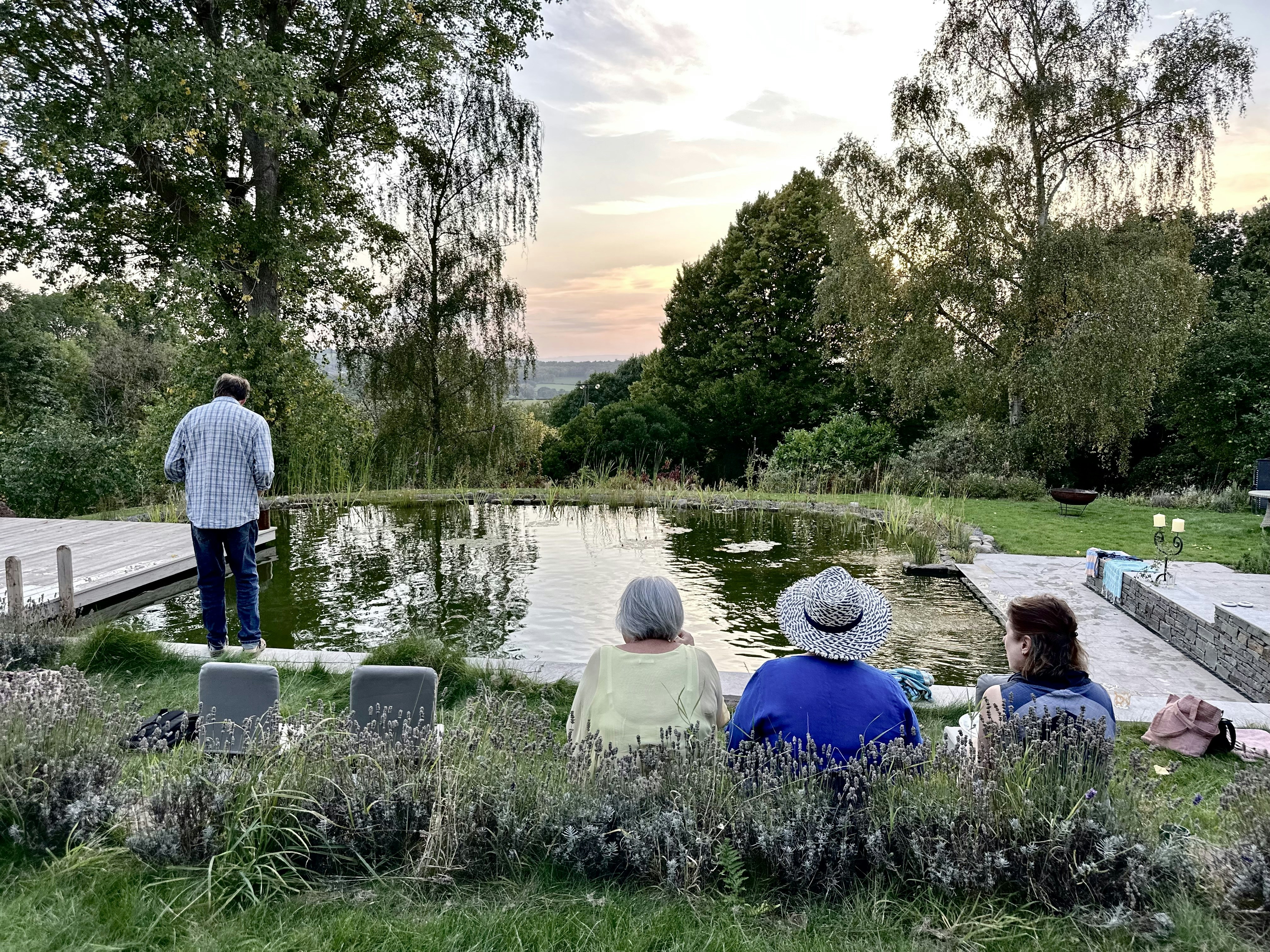 A group of people sitting next to a pond photo – Free Nature Image on ...