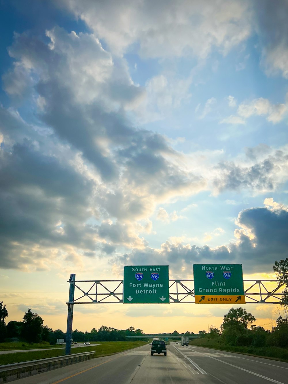 two highway signs on a highway with a sky background