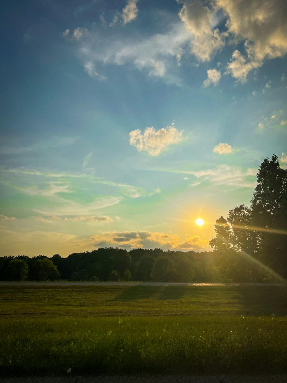 the sun is setting over a grassy field