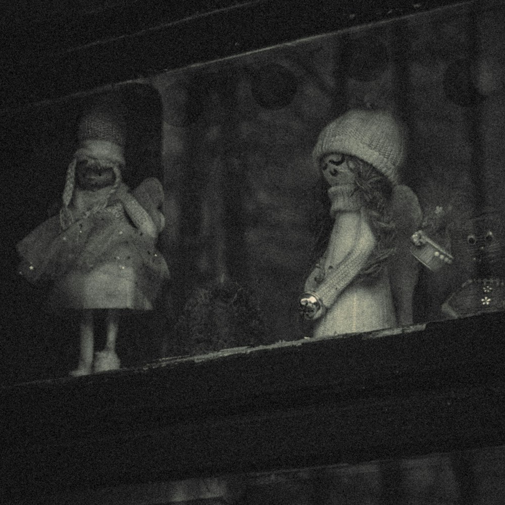 a couple of dolls sitting on top of a window sill