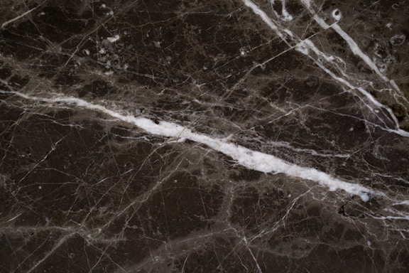Close-up of a polished marble countertop with warm lighting highlighting its texture.