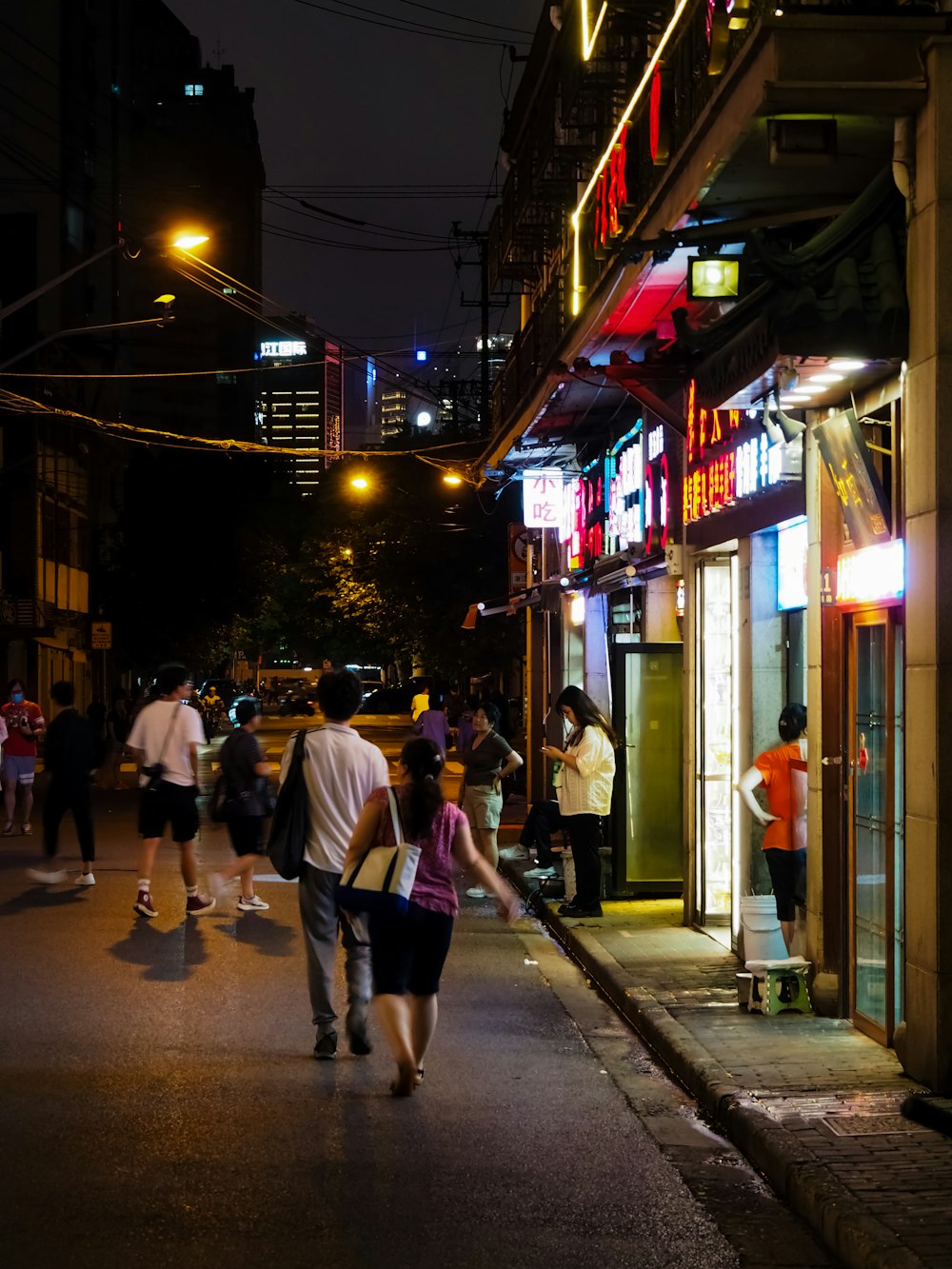 a group of people walking down a street at night