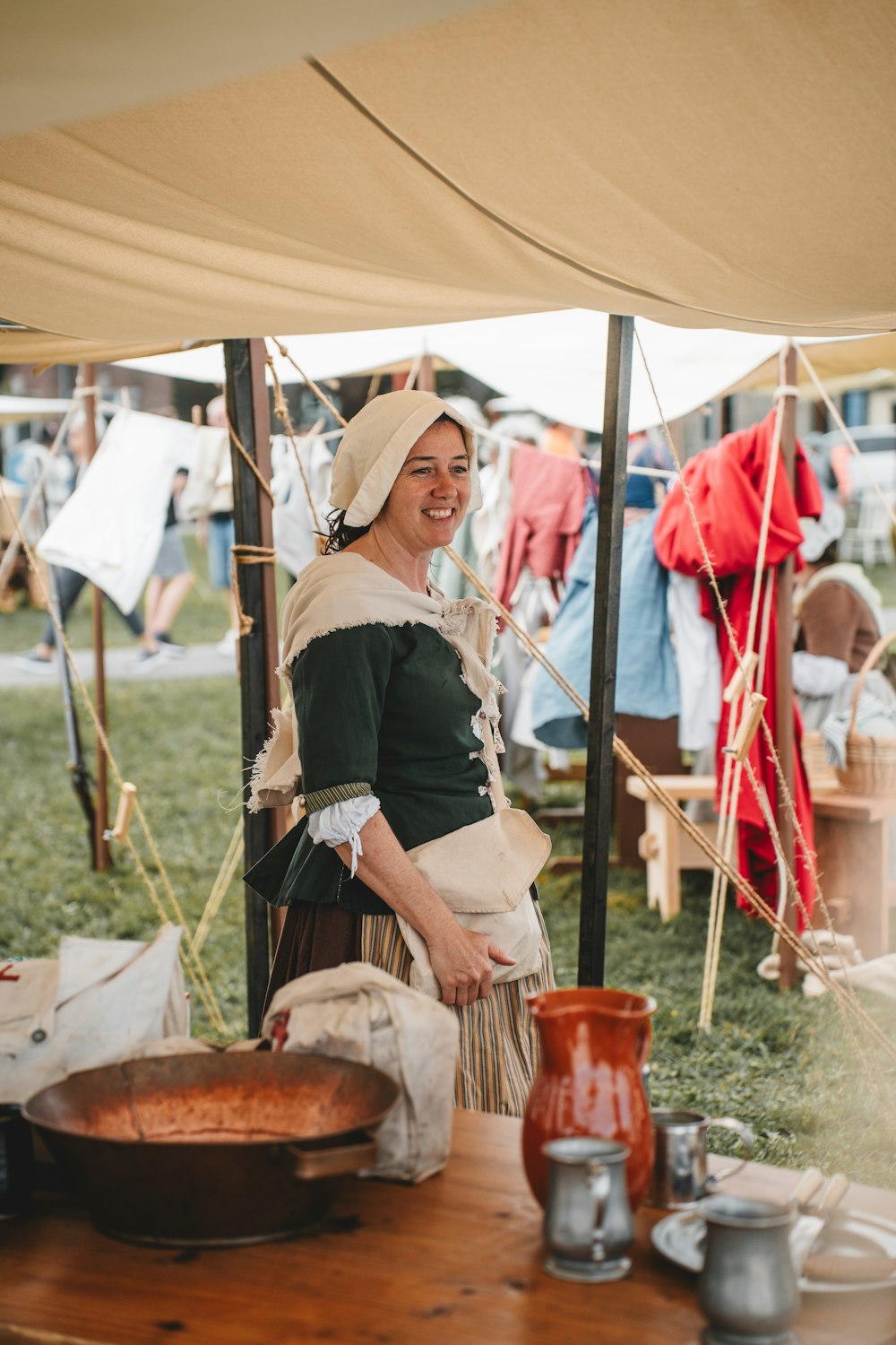 Une femme en bonnet sourit alors qu’elle se tient devant une table avec un