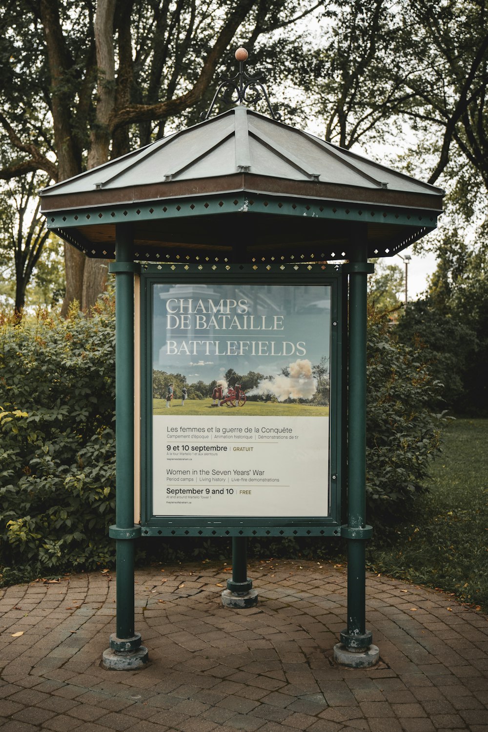 a sign on a brick walkway in front of a tree