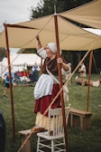 An actress in vintage costume engaging with guests at a lively outdoor event.