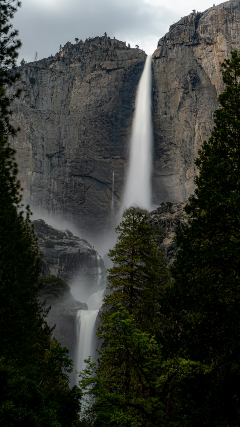 a tall waterfall is seen through the trees