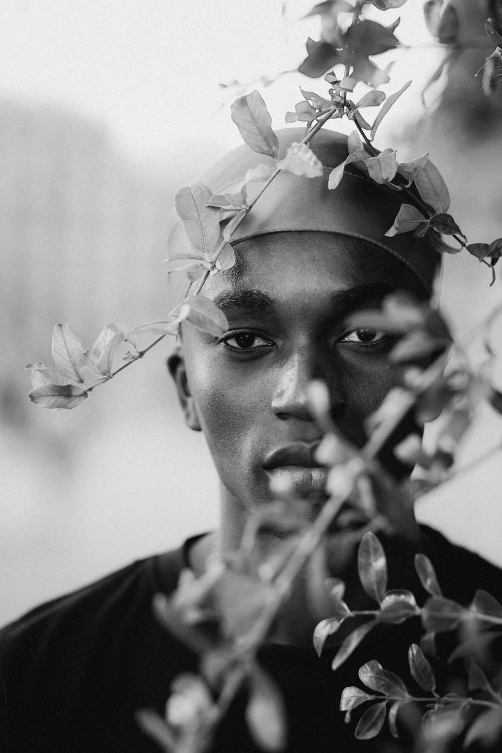 a black and white photo of a man with leaves on his head