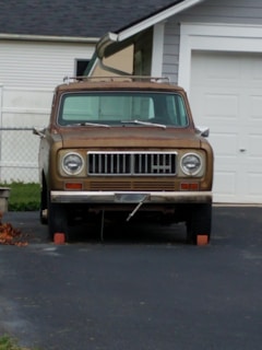 A tidy driveway featuring a trusted older vehicle with subtle signs of everyday use.
