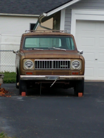 An old, rusty sedan parked in a driveway, ready to be donated.