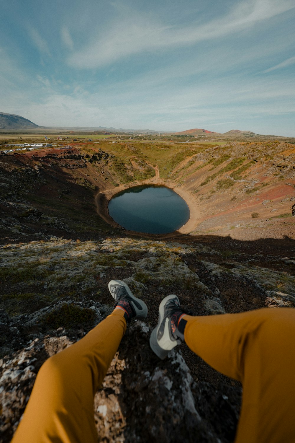 a person standing on top of a mountain next to a lake