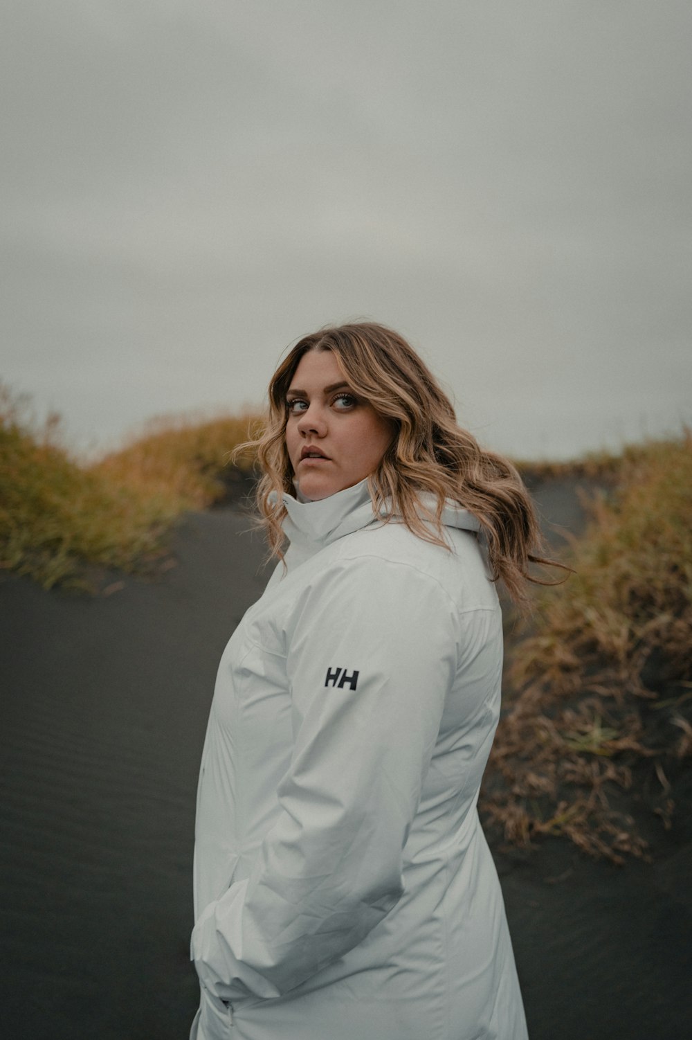 Une femme en veste blanche debout sur une plage