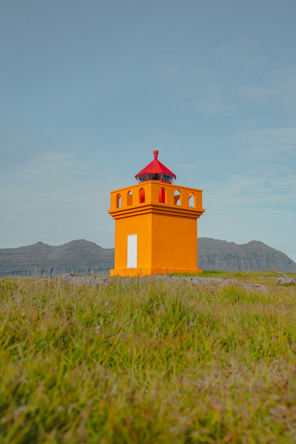 a yellow tower with a red roof in a field