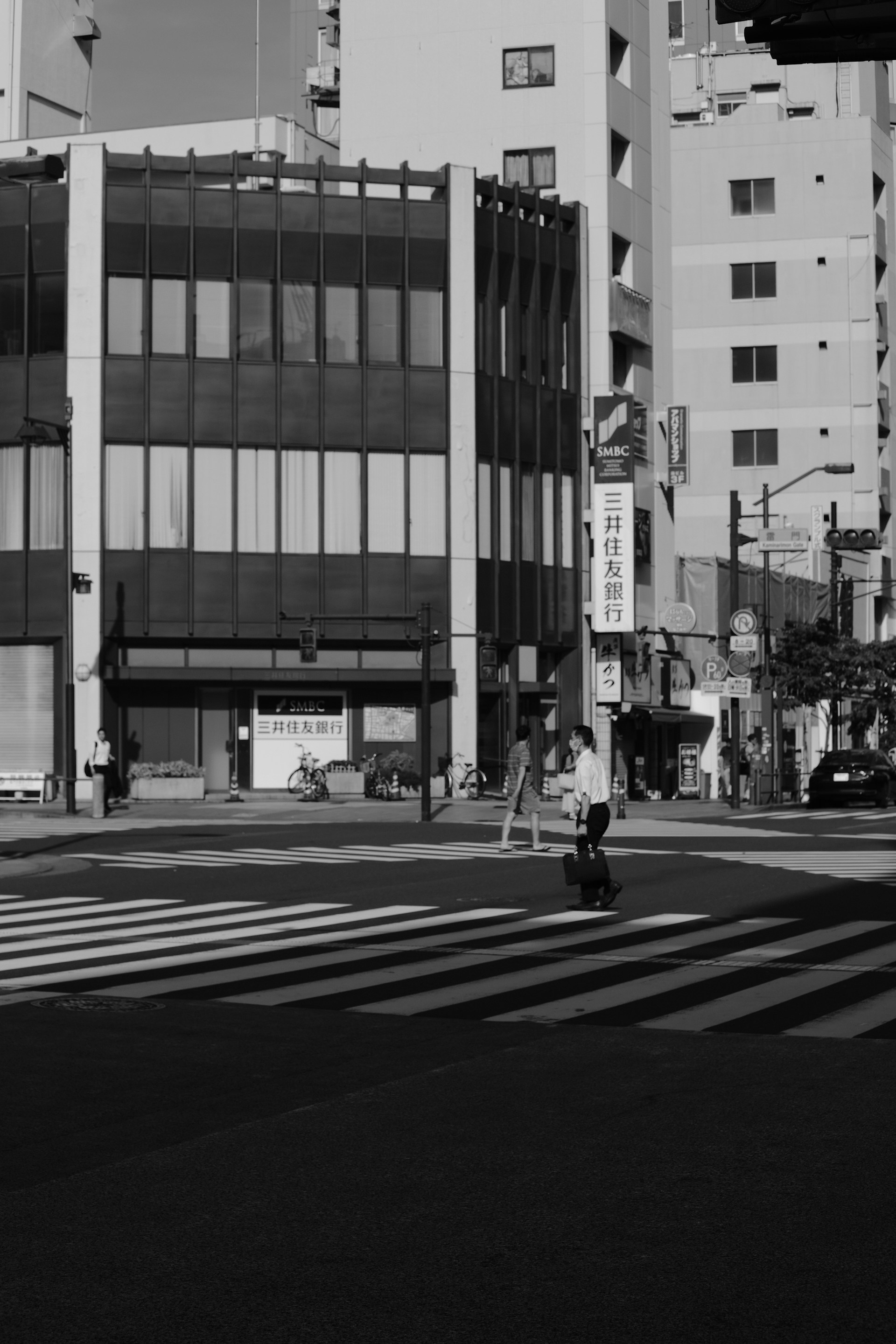 A striking monochrome street photograph capturing a candid moment of a passerby framed by urban shadows.
