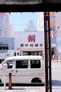 A white cargo van parked outside a busy loading dock.