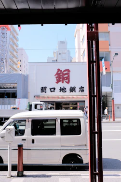 A clean, modern van parked in front of a city building on a sunny day.