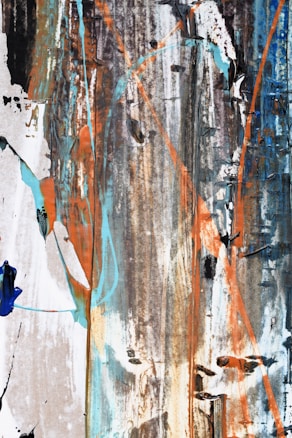 An abstract artwork featuring vertical streaks of color and texture, including splashes of blue, orange, and white. The composition is layered with varying shades of brown and black, creating a rustic and weathered appearance.