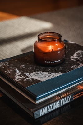 A rich vanilla candle melting slowly beside a stack of vintage books and a cup of tea.