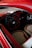 A vintage car interior with a retro-styled steering wheel and dashboard. The seats have a quilted pattern with red and beige colors, and the door panels are detailed with artistic accents.