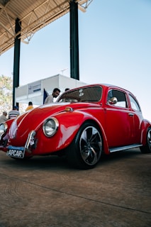 A vibrant 1960s Volkswagen Transporter T1 parked at a sunny retro car show with club members admiring it.
