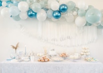 a table topped with lots of blue and white balloons