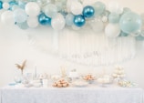 a table topped with lots of blue and white balloons