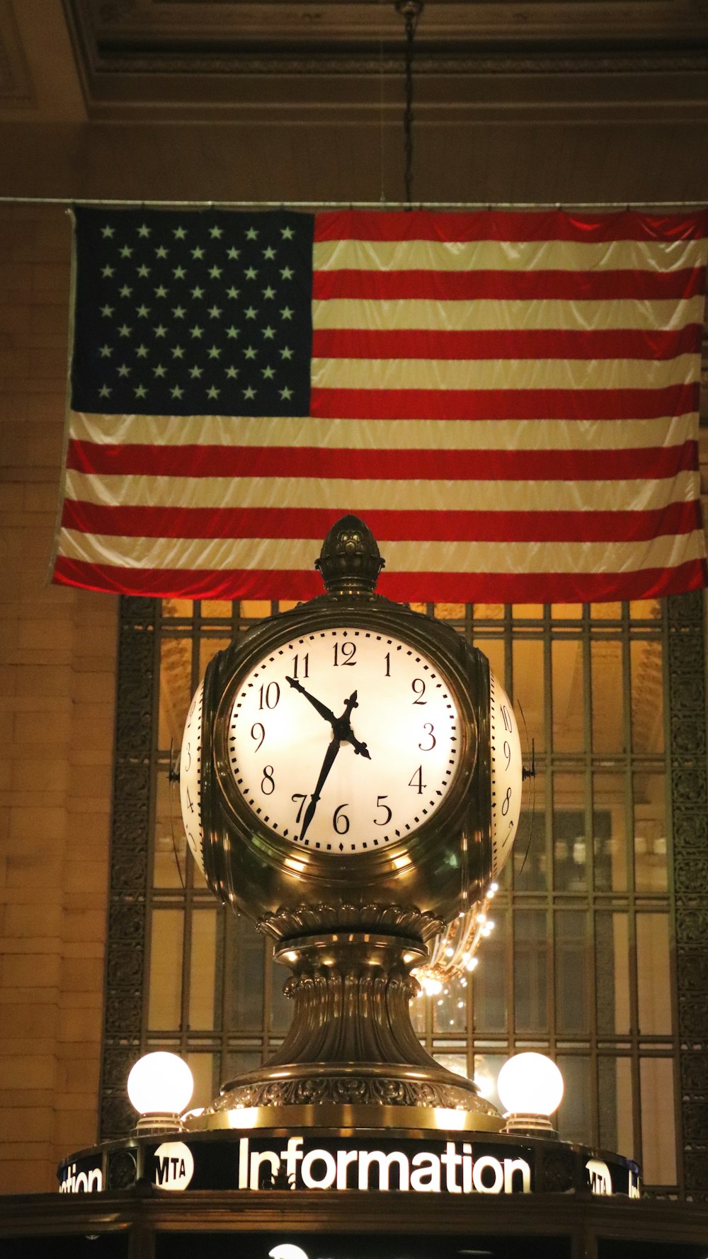 a large clock sitting in front of an american flag