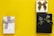 Three gift boxes are arranged on a bright yellow background. The first box is wrapped in pale paper with a gray ribbon and a small tag. The second box is smaller, wrapped in gold paper with a brown ribbon. The third box is black with a black ribbon featuring gold text.