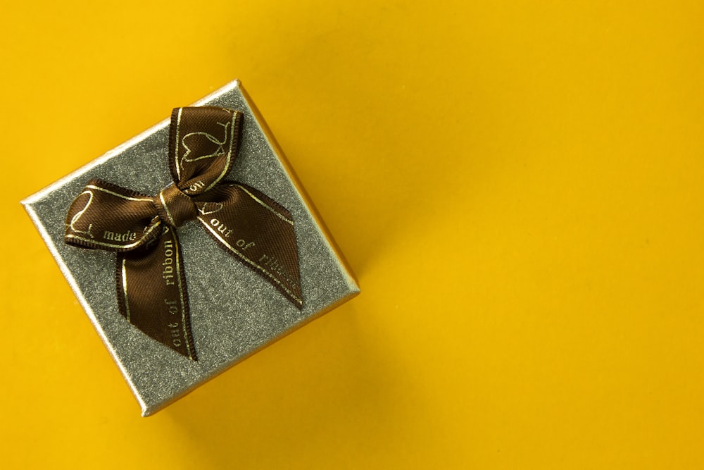 a gift box with a brown bow on a yellow background