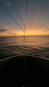 the sun is setting over the ocean as seen from a boat