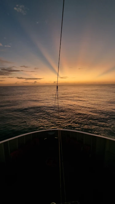 the sun is setting over the ocean as seen from a boat