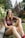 A smiling woman sitting in a serene garden.