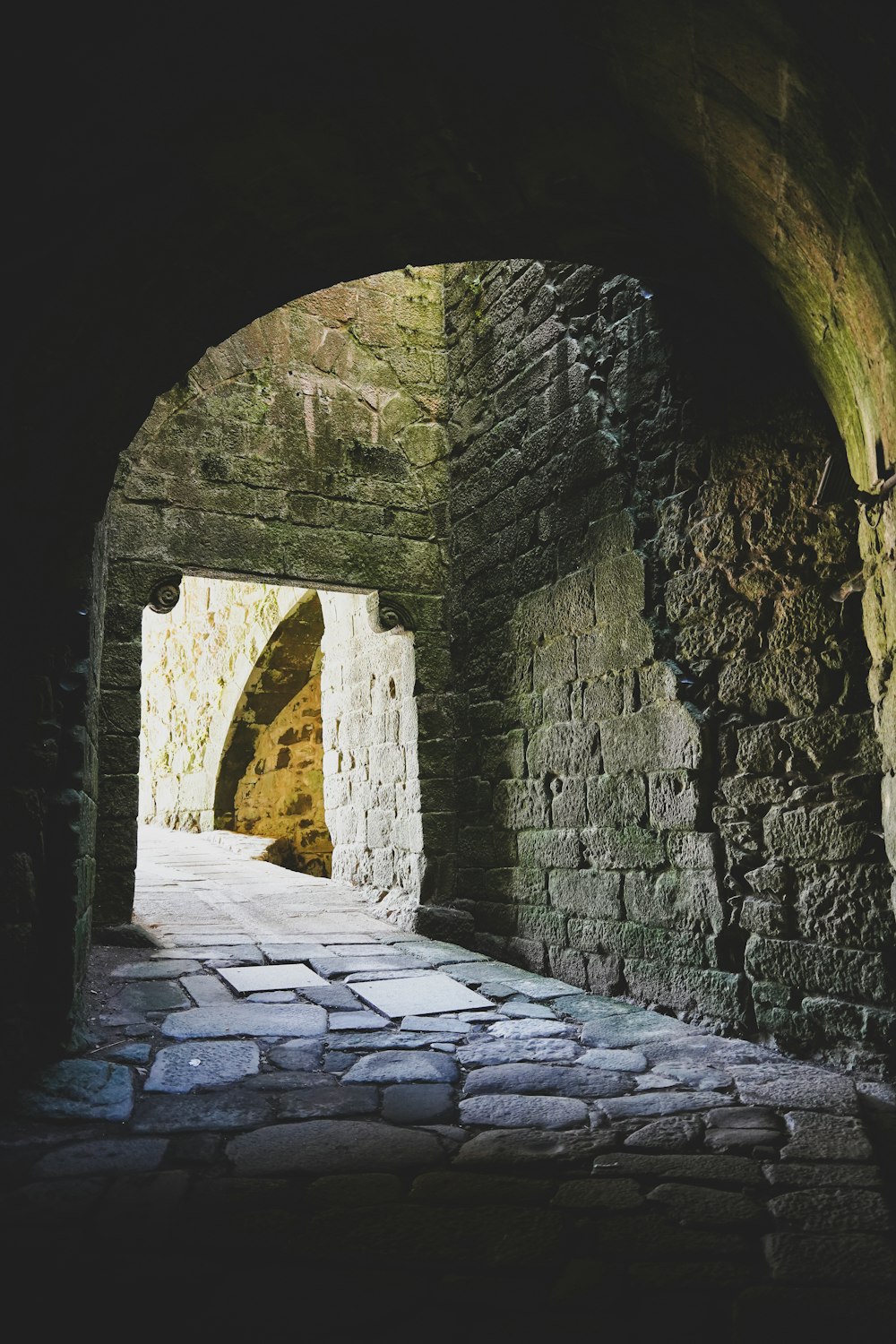 a tunnel in a stone wall with a light at the end