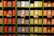 A set of neatly organized shelves displaying a variety of colorful canned seafood. The cans are arranged by type and color, featuring bright red, blue, and green labels. Some cans have decorative illustrations and tags with pricing, showcasing a vibrant and appealing presentation.