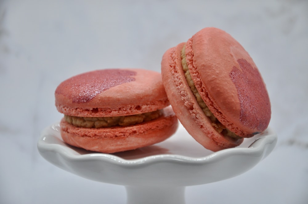 Deux macarons roses assis sur une assiette blanche