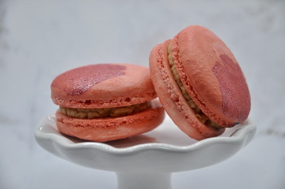 two pink macaroons sitting on a white plate