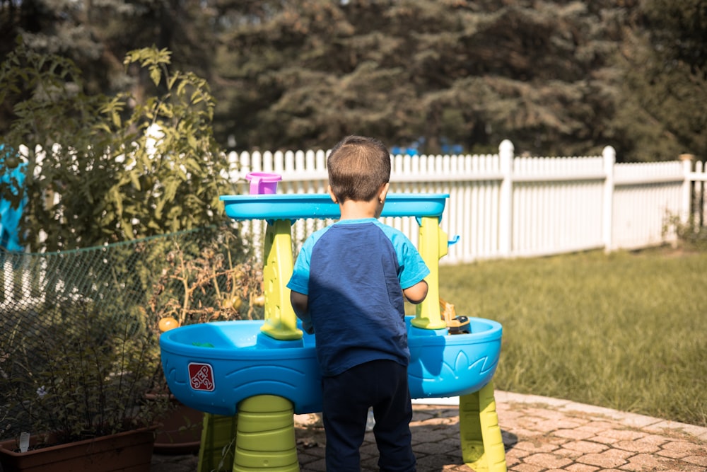 a young boy playing in a blue and yellow water table
