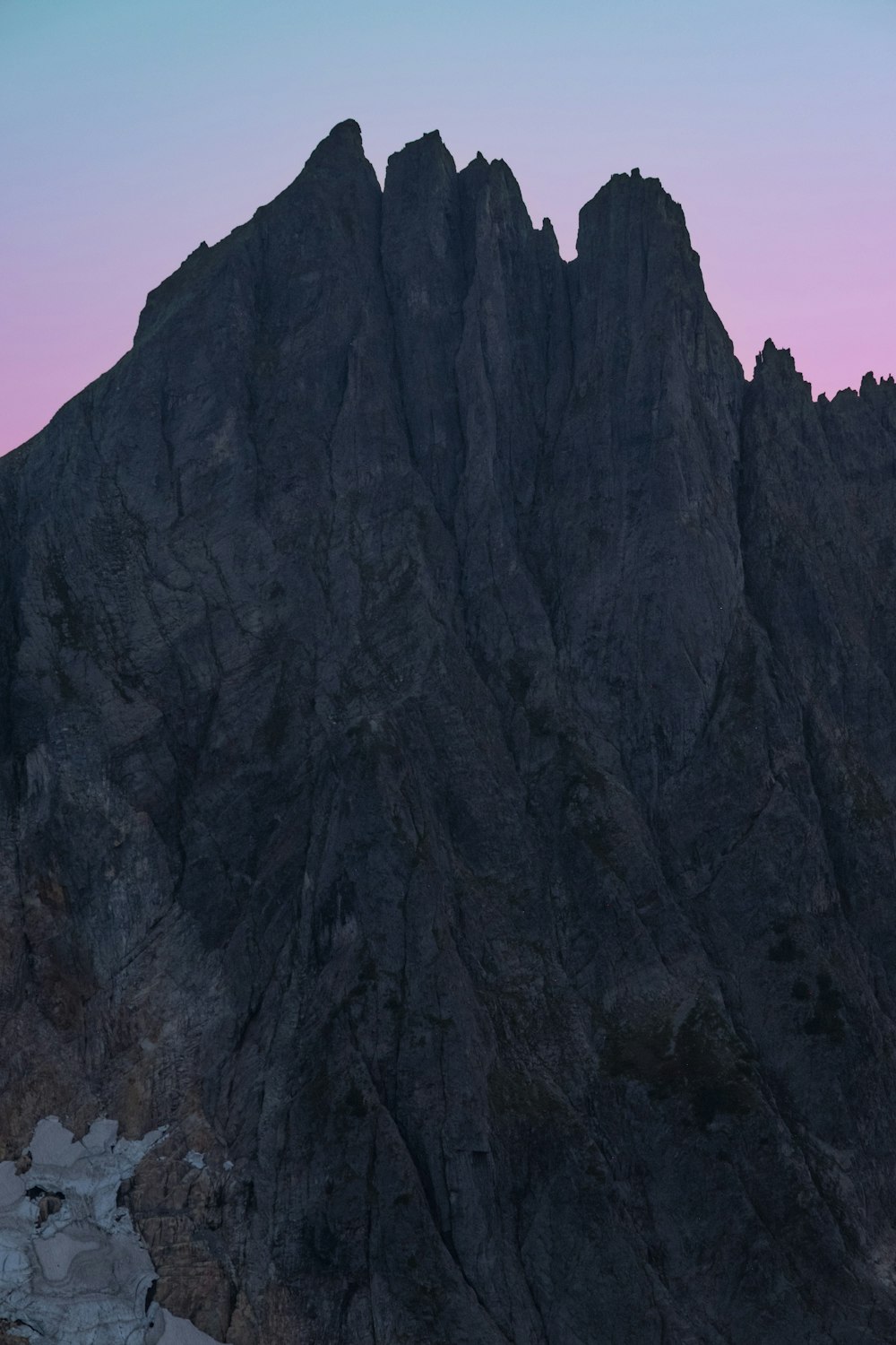 a very tall mountain with a pink sky in the background