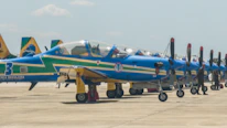 A row of powered parachutes protected by Vientoguard covers at an outdoor aviation event.