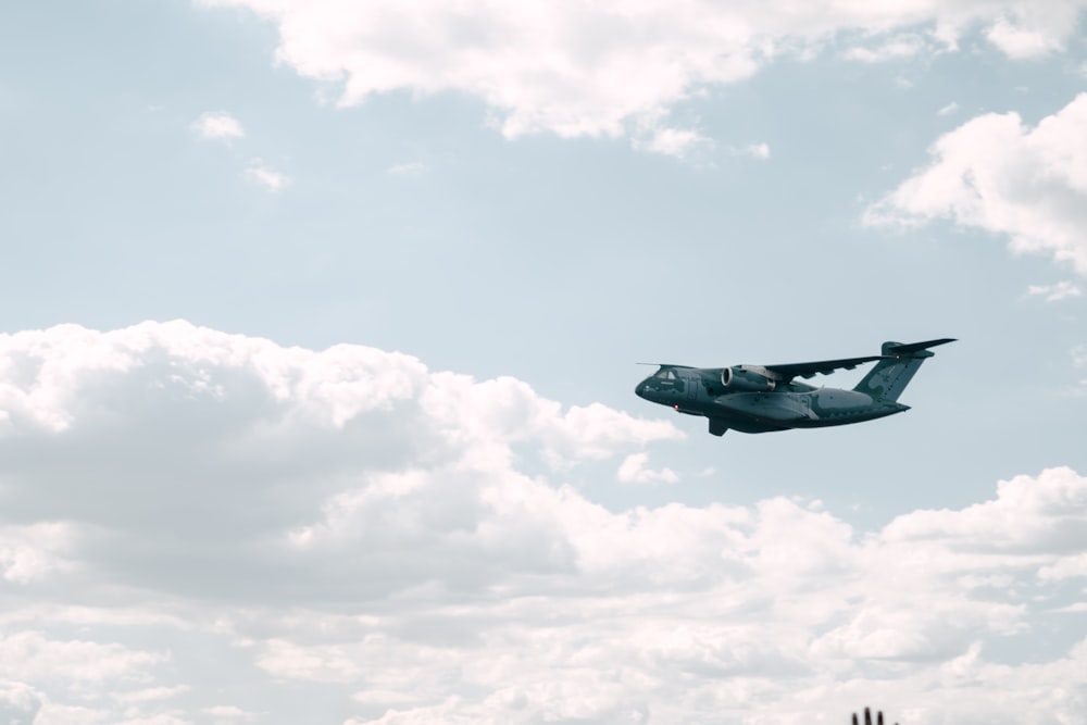 a plane flying in the sky with clouds in the background