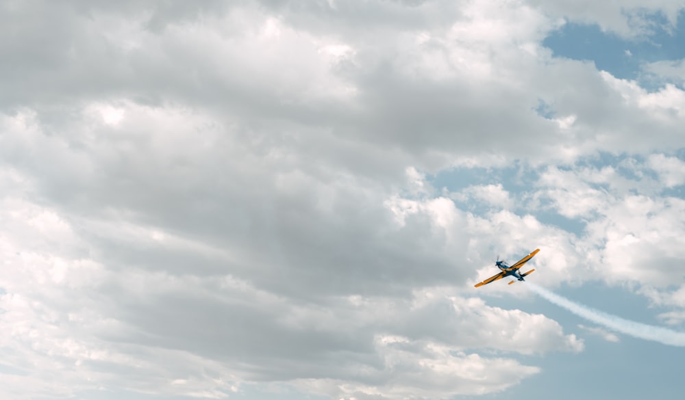 a small plane flying through a cloudy blue sky