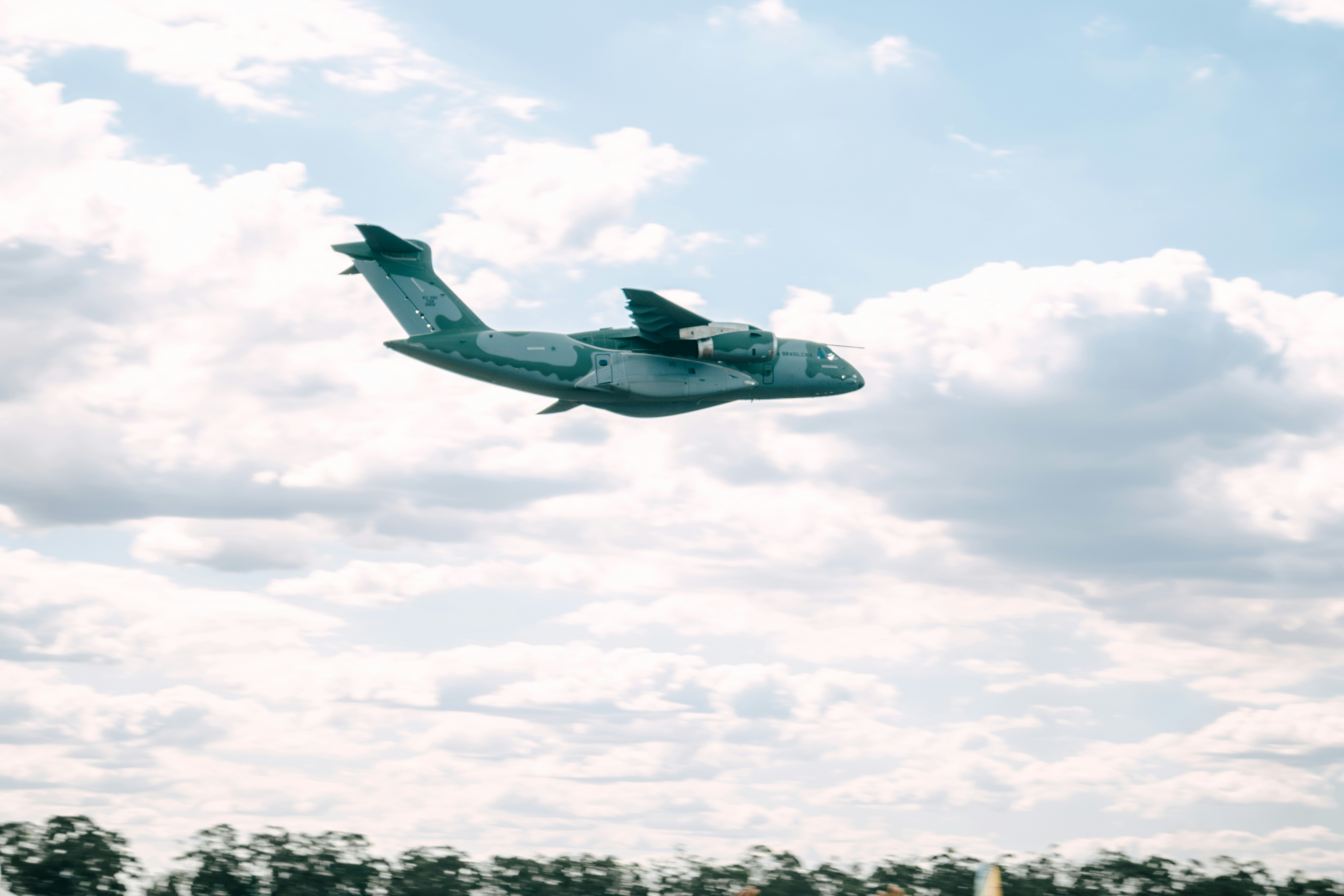 a small airplane flying through a cloudy blue sky, 