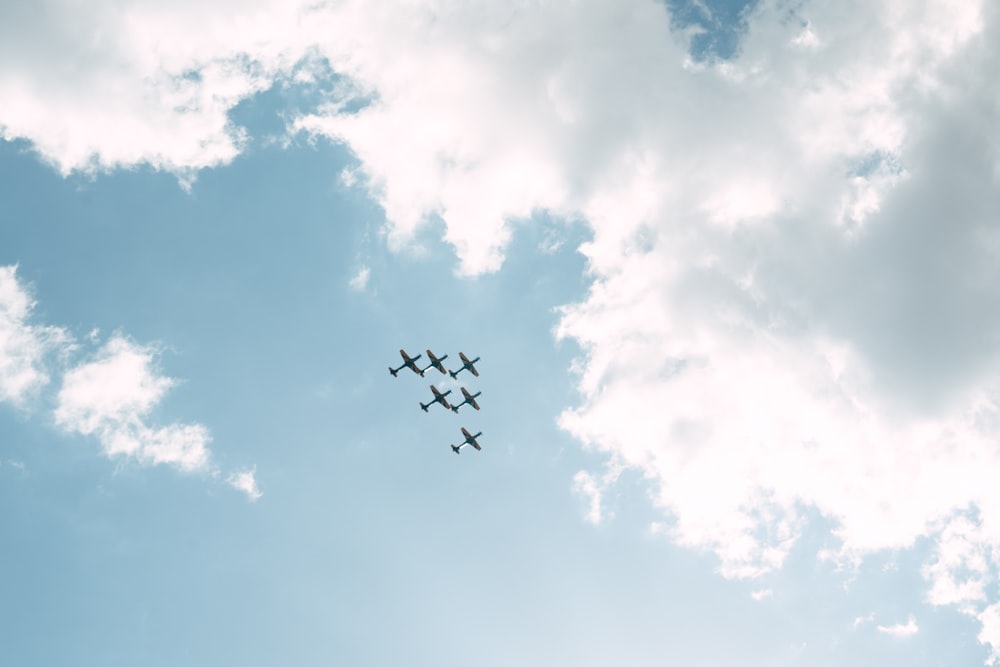 a group of four airplanes flying through a cloudy sky